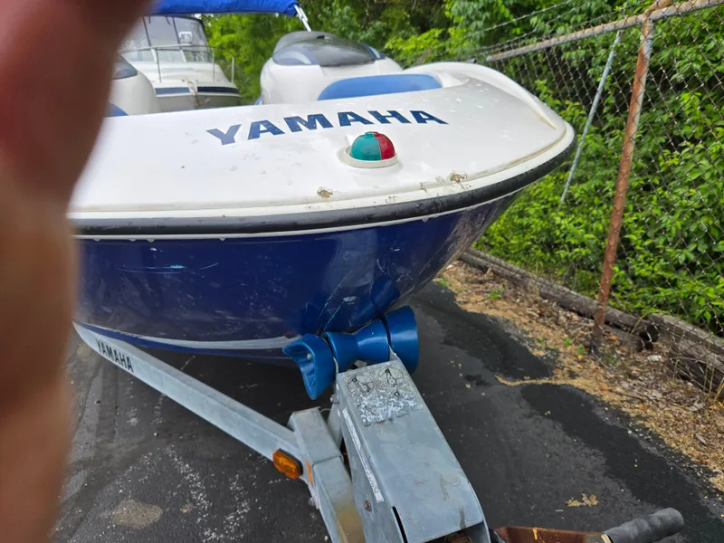 Slide: The Image of 2004 Yamaha Boats 210 LX on trailer, parked near a fence with greenery. - 6