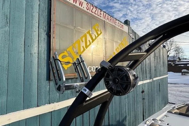 Slide: The Image of 2025 Tahoe 2150 boat with wakeboard rack and speaker, Sizzle Marine sign in background. - 36