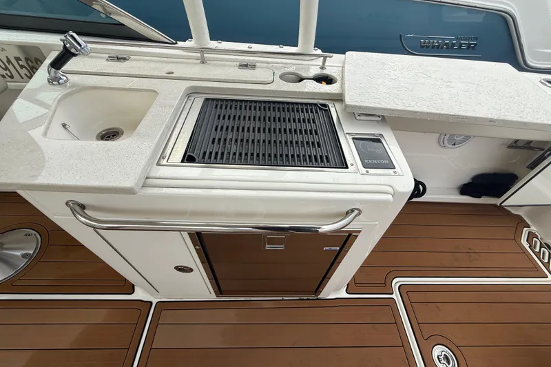 Slide: The Image of 2018 Boston Whaler 270 Vantage boat kitchen with sink, grill, and wooden deck. - 9