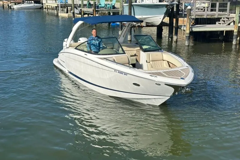 Slide: The Image of 2019 Regal 29 OBX boat cruising in a marina with a blue canopy. - 14