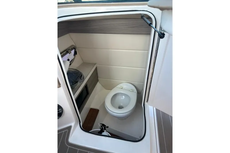 Slide: The Image of 2019 Regal 29 OBX boat interior bathroom with compact toilet and storage shelf. - 47