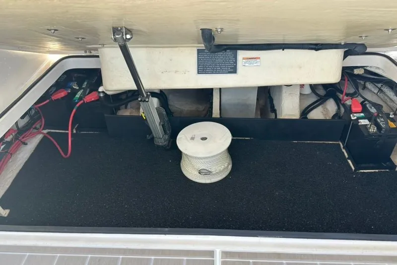 Slide: The Image of 2019 Regal 29 OBX boat storage compartment with battery and rope spool. - 64
