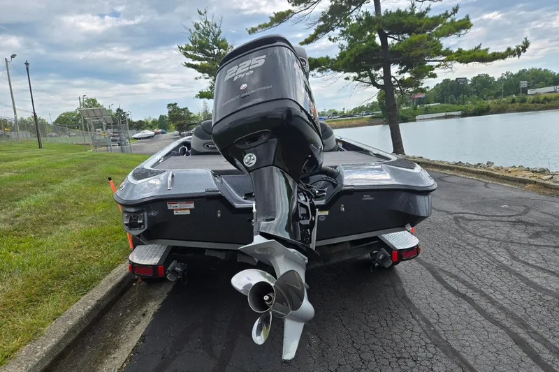 Slide: The Image of 2014 Triton 19XS boat with 225 Pro engine, parked near a lake under cloudy skies. - 2