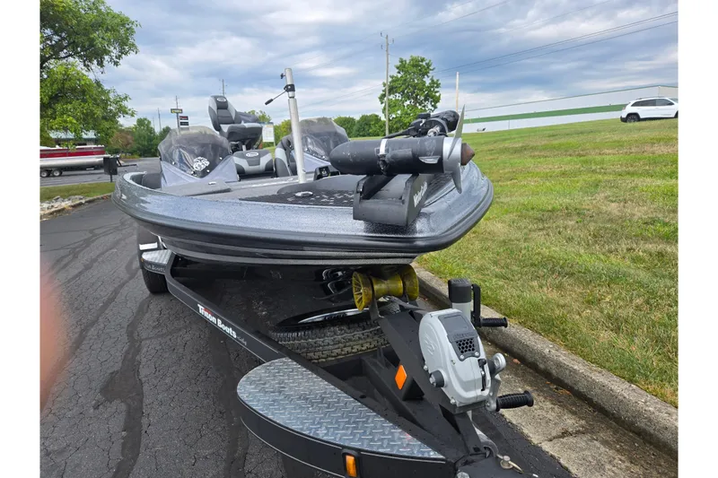 Slide: The Image of 2014 Triton 19XS boat on trailer, parked on asphalt near grassy area. - 6