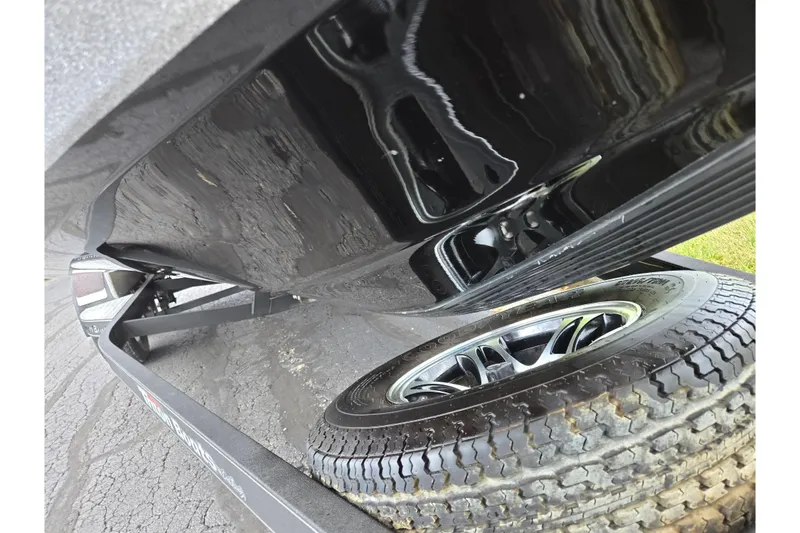 Slide: The Image of 2014 Triton 19XS boat trailer with shiny black hull and tire detail. - 7