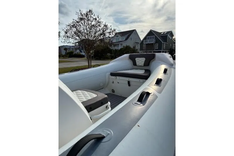 Slide: The Image of 2021 Highfield Sport 520 boat with cushioned seating, parked in a residential area. - 4