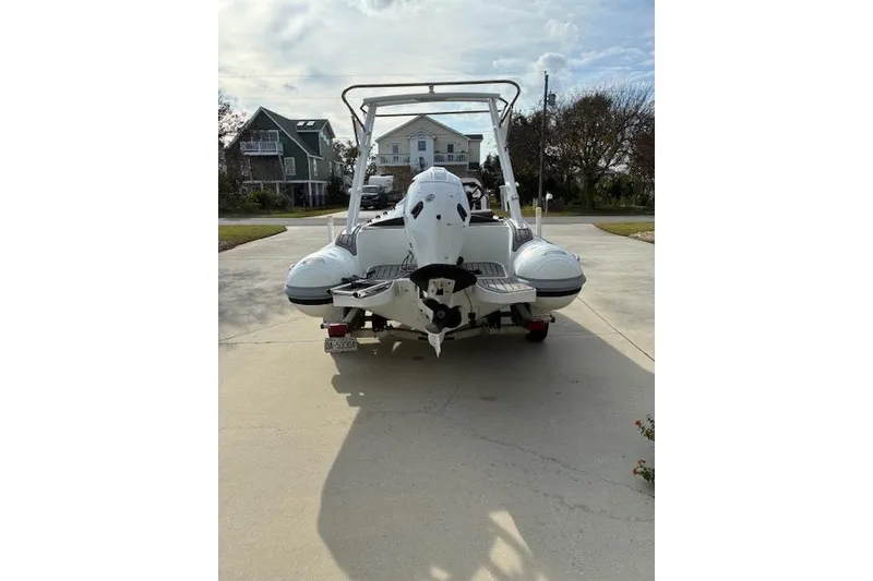 Slide: The Image of 2021 Highfield Sport 520 boat on a driveway, rear view with houses in the background. - 9