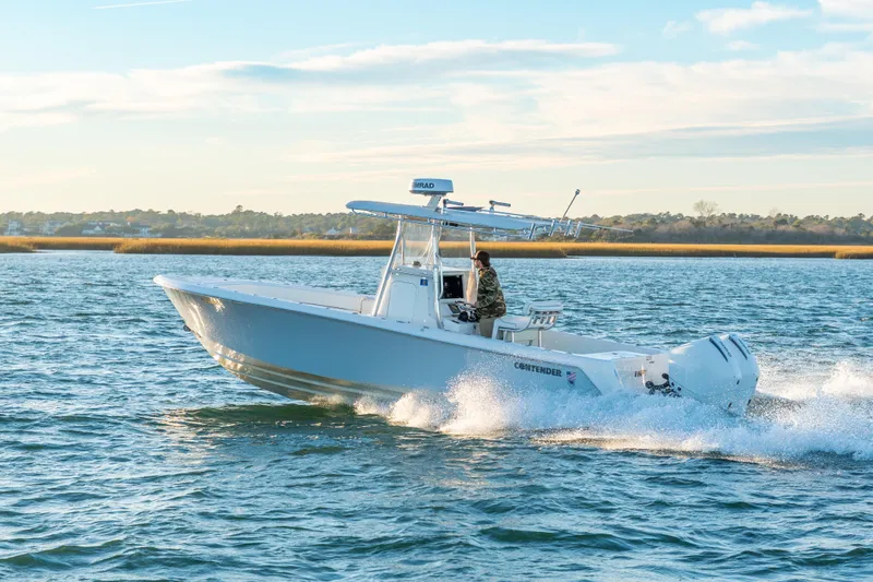 Slide: The Image of 2023 Contender 28 Sport boat cruising on open water under a clear sky. - 3