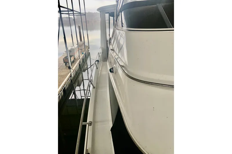 Slide: The Image of 2005 Carver 444 Cockpit Motor Yacht docked, side view with railing and calm water. - 35