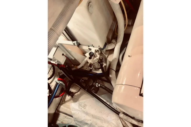 Slide: The Image of Engine room of 2005 Carver 444 Cockpit Motor Yacht with visible hoses and components. - 76