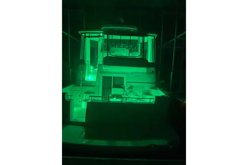 Slide: The Image of 2005 Carver 444 Cockpit Motor Yacht illuminated with green lights at night. - 12
