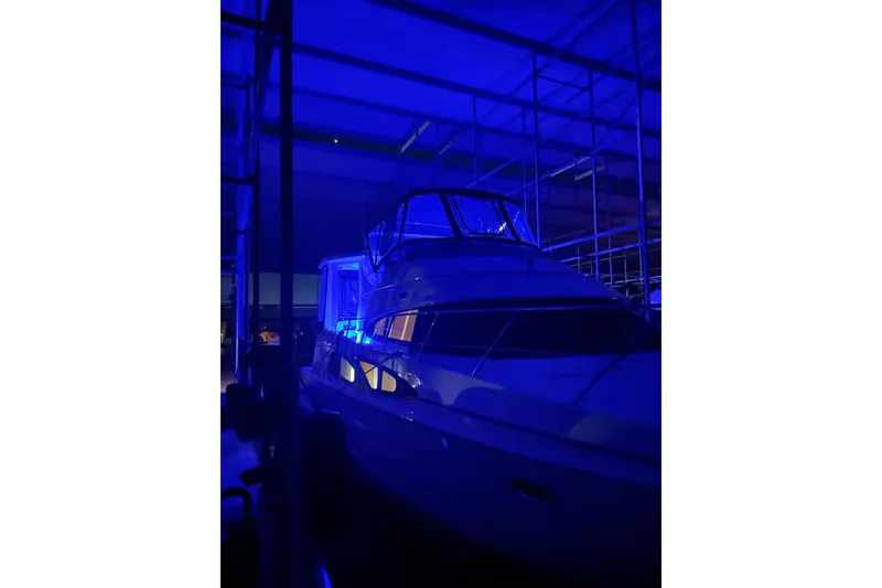 Slide: The Image of 2005 Carver 444 Cockpit Motor Yacht illuminated in blue light inside a marina. - 14