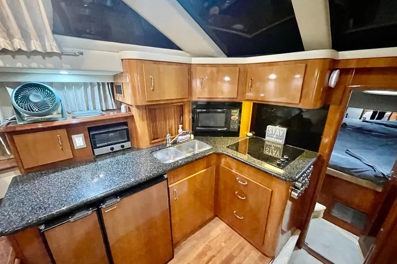 Slide: The Image of Luxurious 2005 Carver 444 Cockpit Motor Yacht kitchen with modern amenities and wood cabinetry. - 57