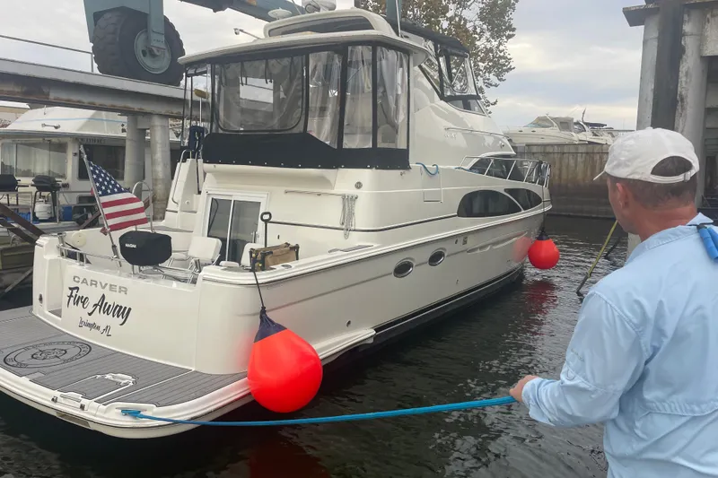 Slide: The Image of 2005 Carver 444 Cockpit Motor Yacht docked with American flag and red buoys. - 6