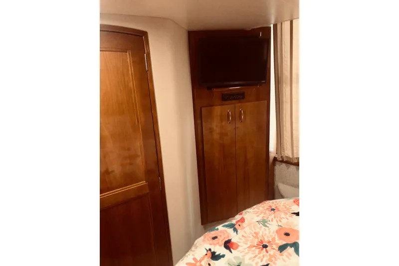 Slide: The Image of 2005 Carver 444 Cockpit Motor Yacht interior with TV, wooden cabinet, and floral bedding. - 70