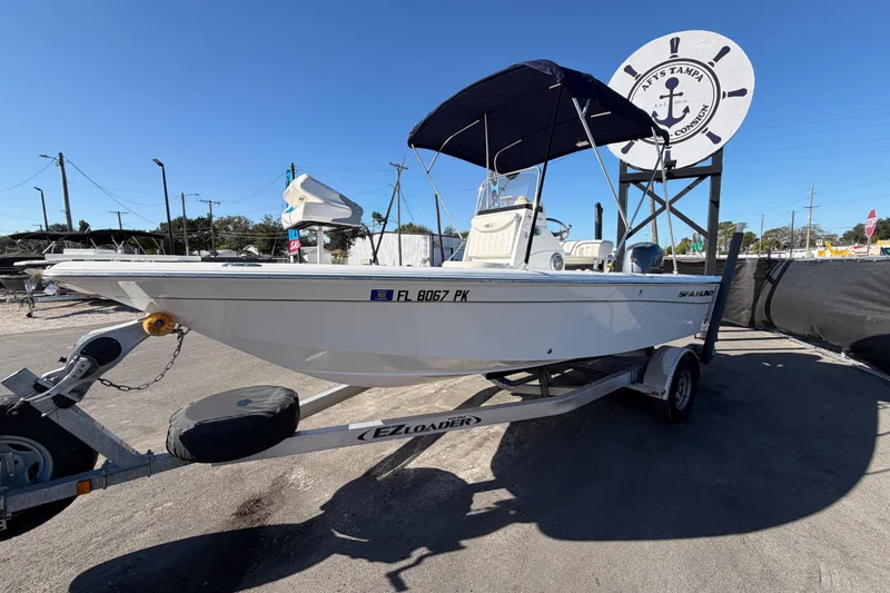 Slide: The Image of 2013 Sea Hunt XP 19 boat on trailer, parked outdoors under clear blue sky. - 10