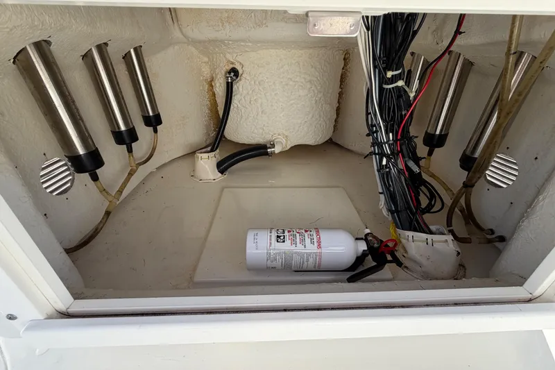 Slide: The Image of 2013 Sea Hunt XP 19 boat compartment with wiring, rod holders, and fire extinguisher. - 28