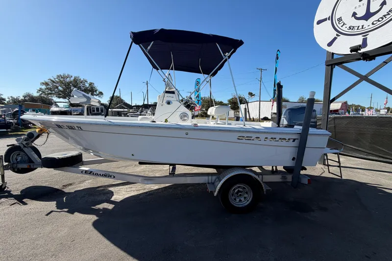 Slide: The Image of 2013 Sea Hunt XP 19 boat on trailer with canopy, parked outdoors. - 9