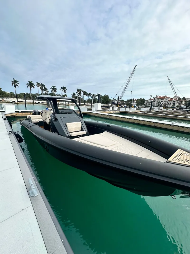 Slide: The Image of 2024 Skipper-BSK 38 boat docked in a marina with palm trees and cranes in the background. - 1