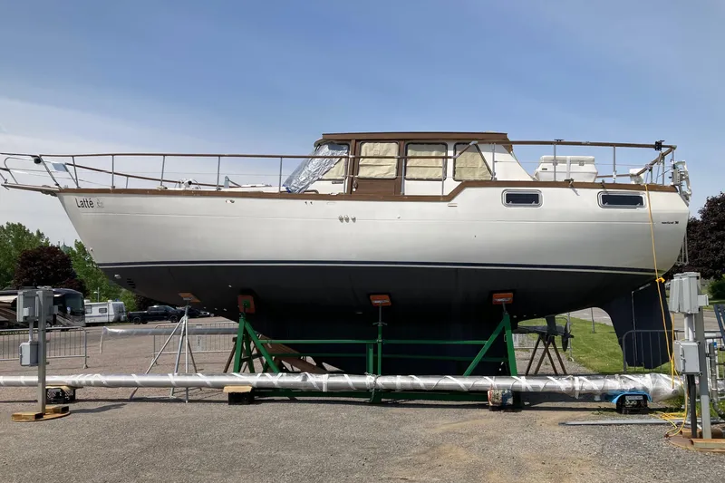 Slide: The Image of 1987 Nauticat 38 sailboat on land, supported by stands, under clear blue sky. - 14
