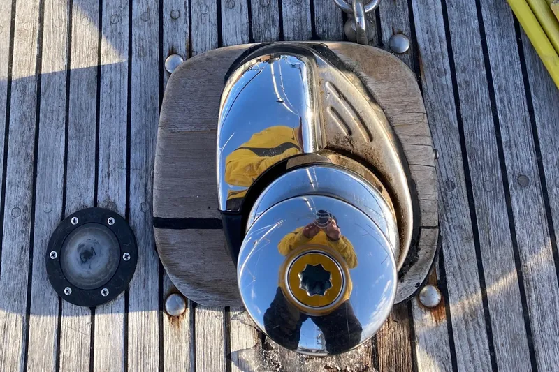 Slide: The Image of Polished winch on 1987 Nauticat 38 sailboat deck, reflecting person in yellow jacket. - 18
