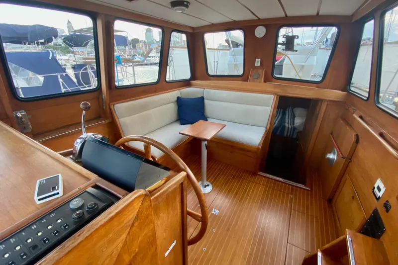 Slide: The Image of 1987 Nauticat 38 interior with wooden helm, seating, and windows overlooking marina. - 28