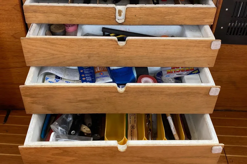 Slide: The Image of Open wooden drawers on a 1987 Nauticat 38, filled with various tools and supplies. - 34