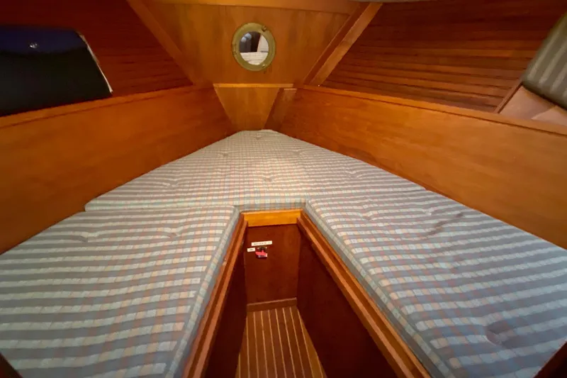Slide: The Image of Cozy cabin interior of 1987 Nauticat 38 sailboat with striped bedding and wooden paneling. - 37