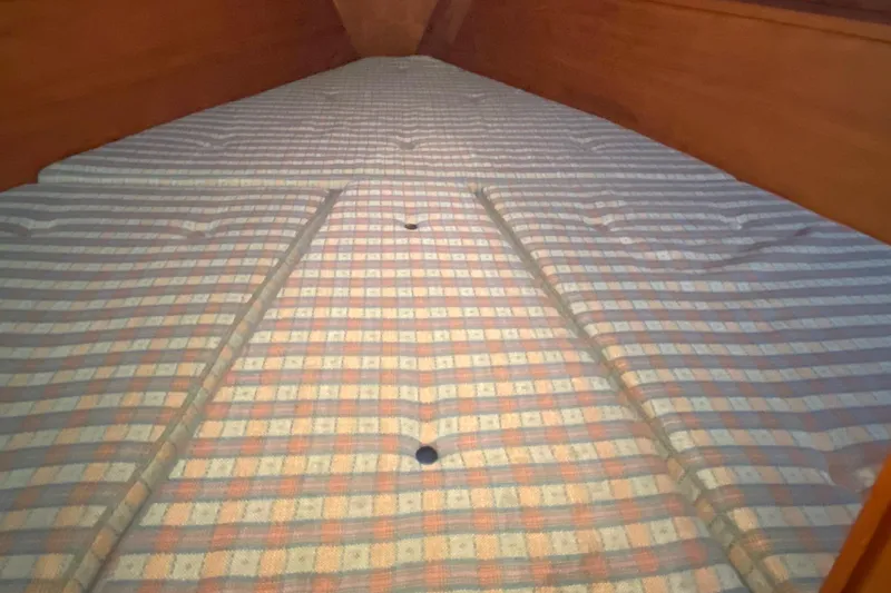 Slide: The Image of Interior cabin view of 1987 Nauticat 38 sailboat with plaid-patterned bedding. - 38