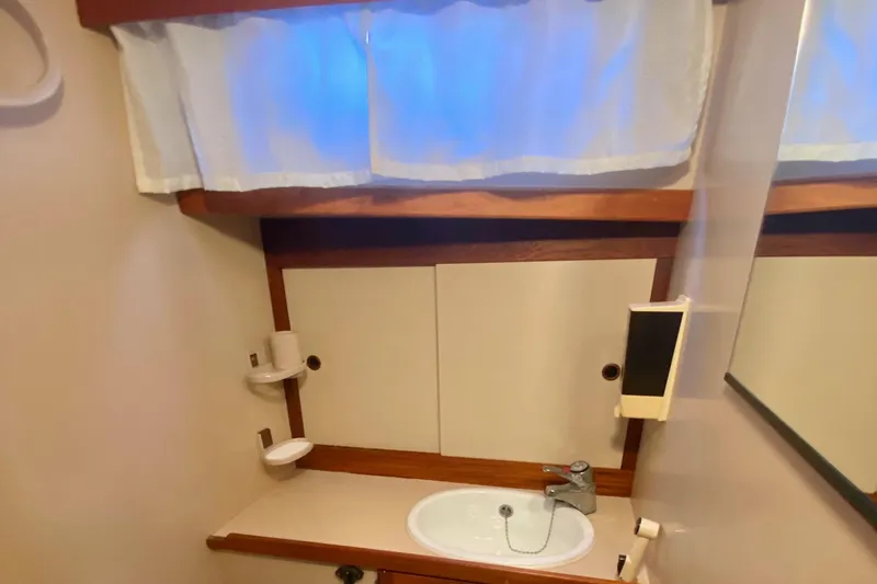 Slide: The Image of 1987 Nauticat 38 yacht bathroom with sink, mirror, and storage cabinets. - 39