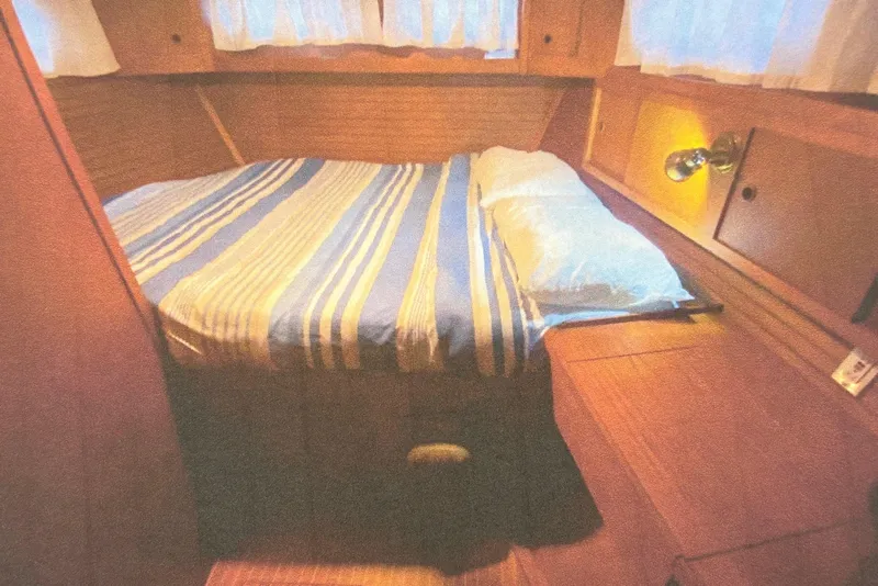 Slide: The Image of Cozy cabin interior of 1987 Nauticat 38 sailboat with striped bedding and wooden furnishings. - 44