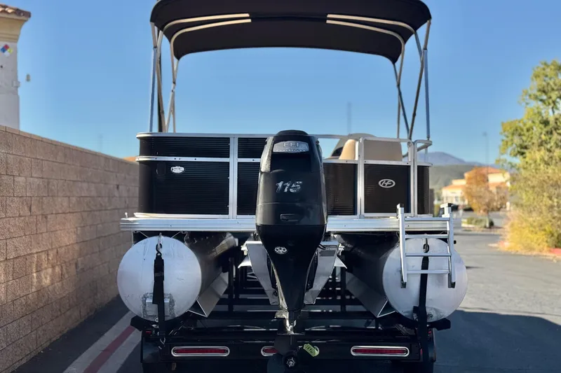 Slide: The Image of 2011 Harris Cruiser 220 CX pontoon boat with outboard motor and canopy, parked outdoors. - 5