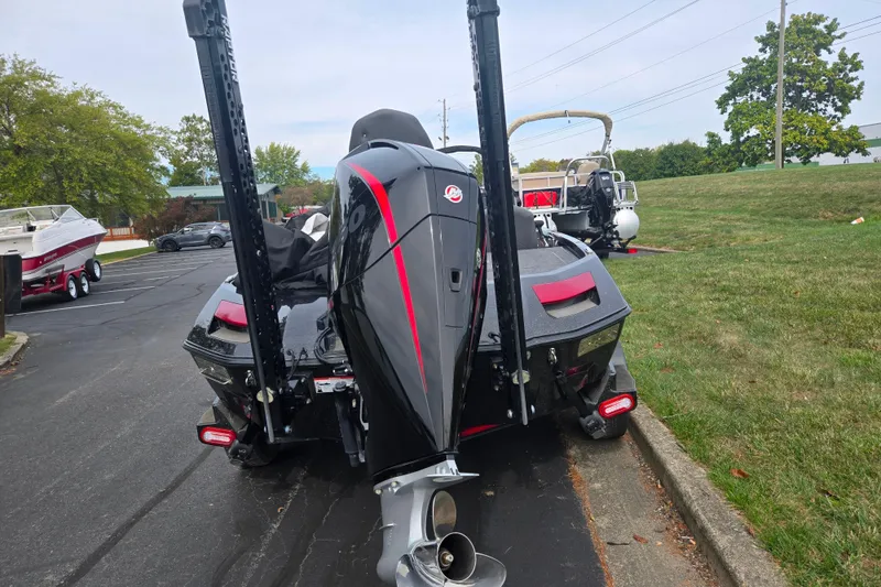 Slide: The Image of 2022 Vexus VX20 boat with powerful outboard motor, parked on pavement near grass. - 2