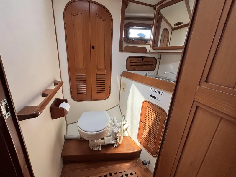Slide: The Image of Wood-paneled bathroom in 1982 Norseman 447 yacht, featuring toilet, sink, and storage cabinets. - 41