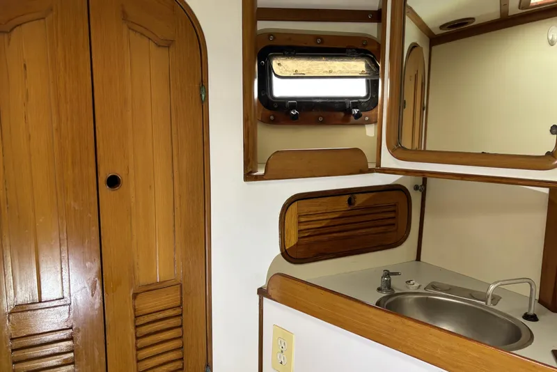 Slide: The Image of 1982 Norseman 447 yacht interior with wooden cabinets, sink, and porthole window. - 43