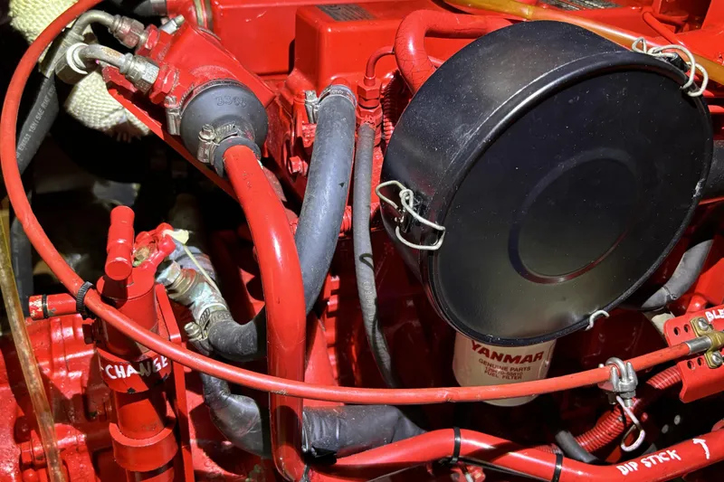 Slide: The Image of Red engine components of a 1982 Norseman 447, featuring hoses and a Yanmar fuel filter. - 67