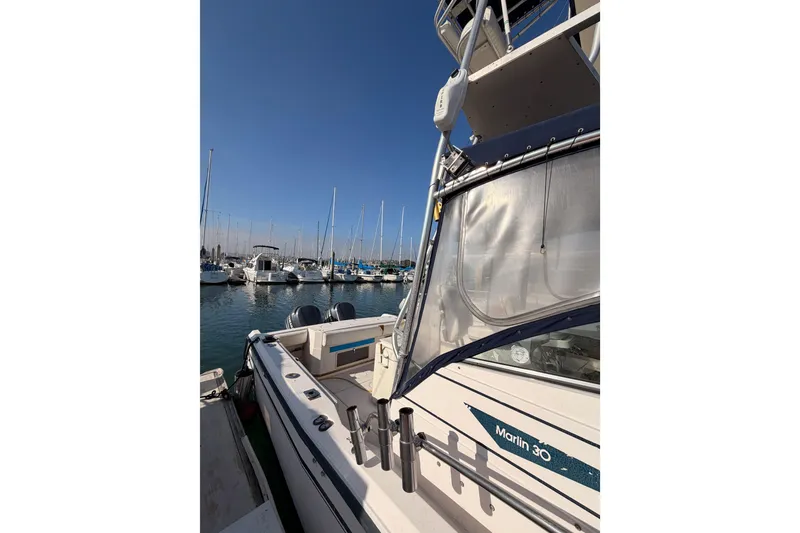 Slide: The Image of 1993 Grady-White Marlin 300 boat docked in a marina under clear blue skies. - 4