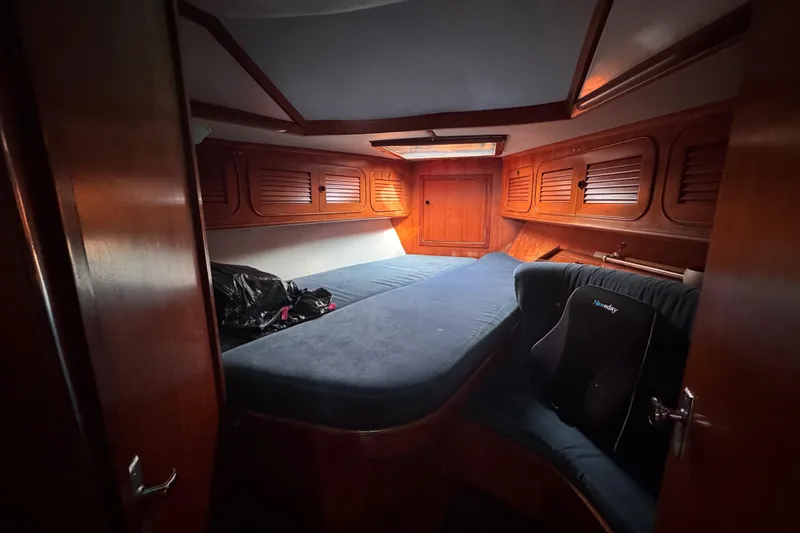 Slide: The Image of Cozy cabin interior of 1989 Hylas 44 sailboat with wooden paneling and blue bedding. - 109