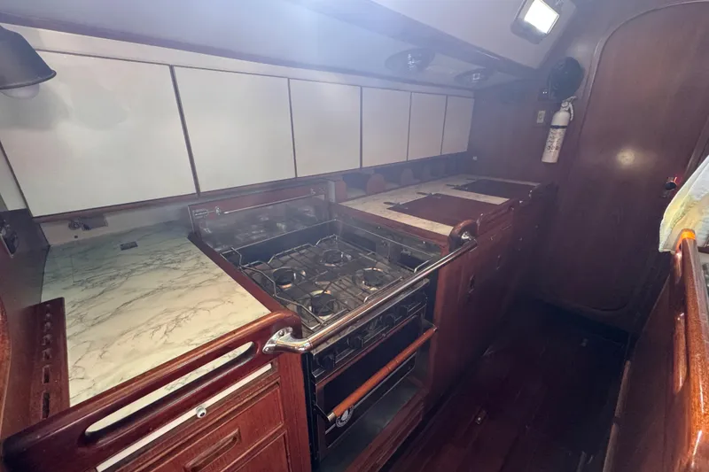 Slide: The Image of 1989 Hylas 44 yacht kitchen with stove, wooden cabinets, and marble countertops. - 111