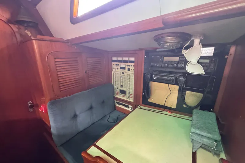 Slide: The Image of Navigation station inside 1989 Hylas 44 yacht with control panels and seating. - 114