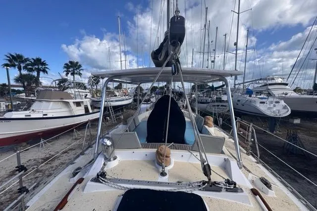 Slide: The Image of 1989 Hylas 44 sailboat docked in a marina, surrounded by other boats and palm trees. - 27