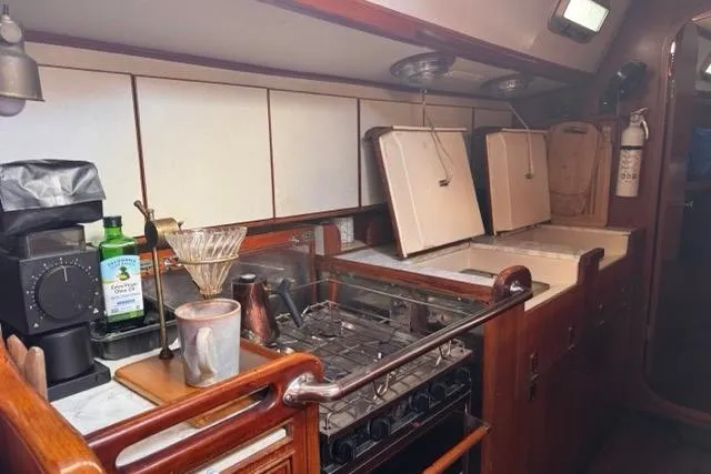 Slide: The Image of 1989 Hylas 44 yacht kitchen with stove, coffee maker, and wooden cabinetry. - 52