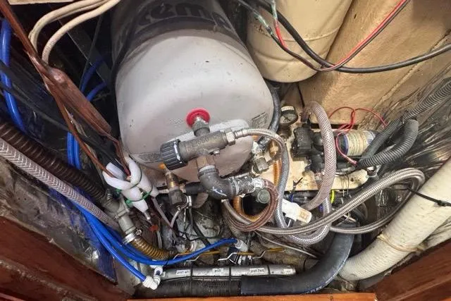 Slide: The Image of Engine compartment of a 1989 Hylas 44 sailboat with various hoses and components. - 84