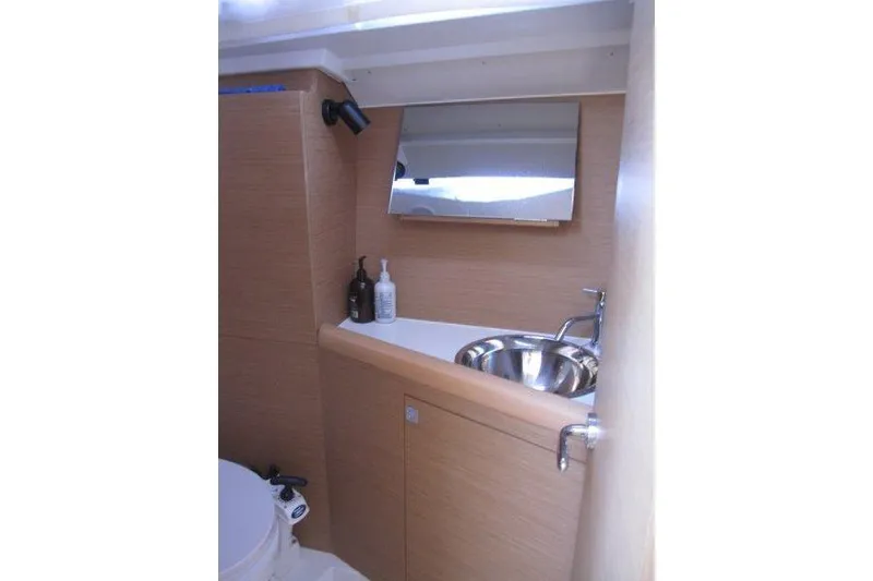 Slide: The Image of 2021 Jeanneau Sun Odyssey 349 bathroom with sink, mirror, and wooden cabinetry. - 16