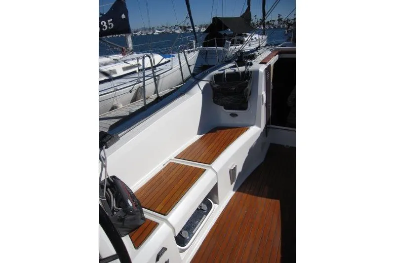 Slide: The Image of 2021 Jeanneau Sun Odyssey 349 sailboat cockpit with wooden seating and marina view. - 29