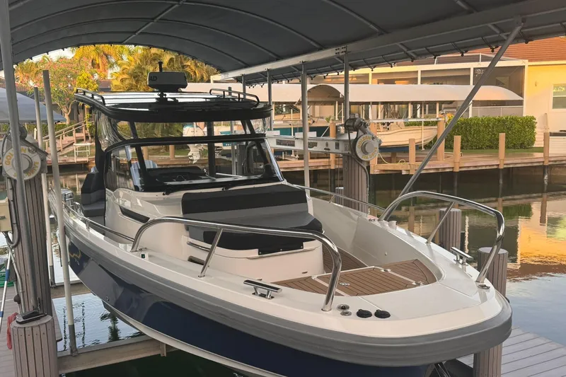 Slide: The Image of Nimbus T9 2021 boat docked under a canopy, surrounded by a serene waterfront setting. - 1