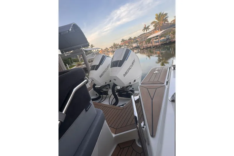 Slide: The Image of 2021 Nimbus T9 boat with dual Mercury outboard engines docked by a scenic waterfront. - 10