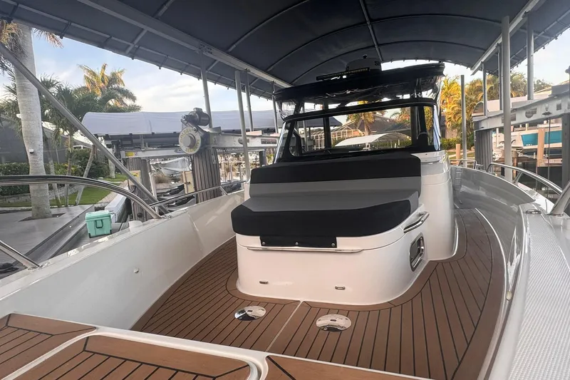 Slide: The Image of 2021 Nimbus T9 boat with sleek design, wooden deck, and comfortable seating under a canopy. - 13