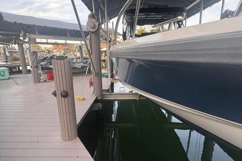 Slide: The Image of Docked Nimbus T9 boat from 2021, with a sleek blue hull, at a marina. - 14