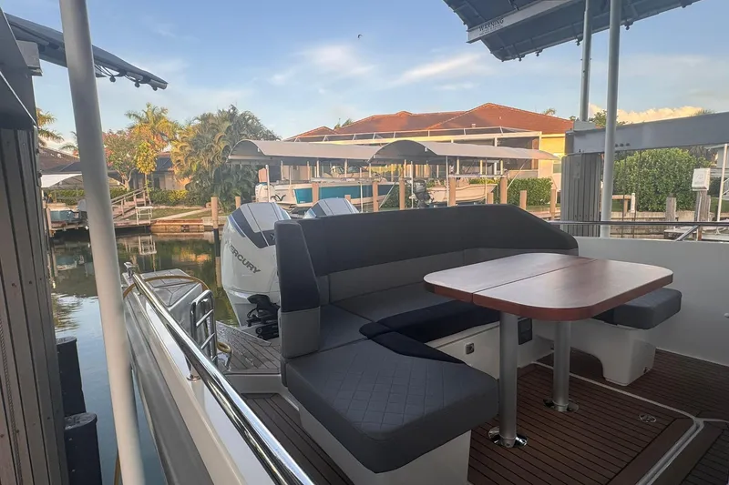Slide: The Image of Nimbus T9 2021 boat with seating area and table, docked in a scenic marina. - 15